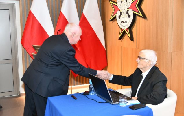 Dwóch prelegentów ściska sobie dłonie.