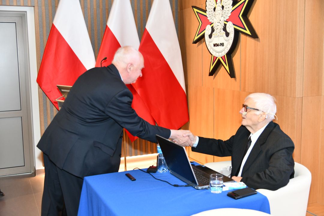 Dwóch prelegentów ściska sobie dłonie.