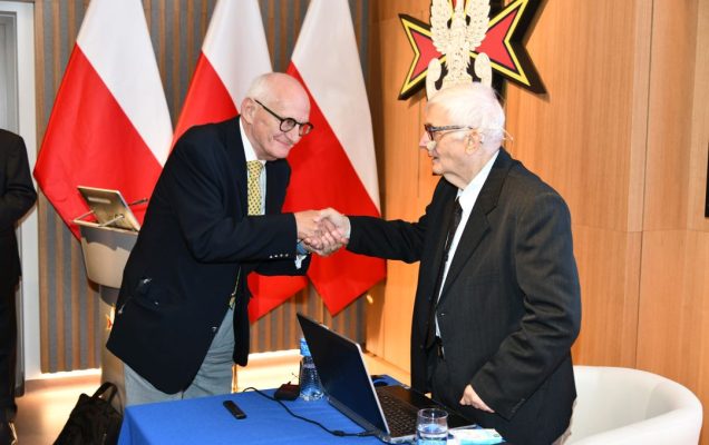 Dwóch prelegentów ściska sobie dłonie.