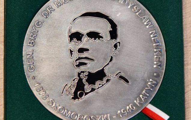 Srebrny medal w aksamitnym zielonym pudełku. Medal przedstawia twarz mężczyzny.