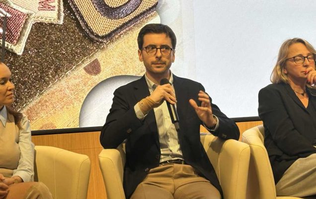 Prelegent podczas panelu. Mężczyzna siedzi w fotelu mówiąc do mikrofonu.
