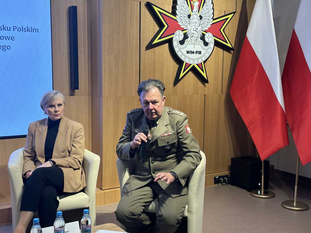 Radosław Tworus siedzi w fotelu mówiąc do mikrofonu.