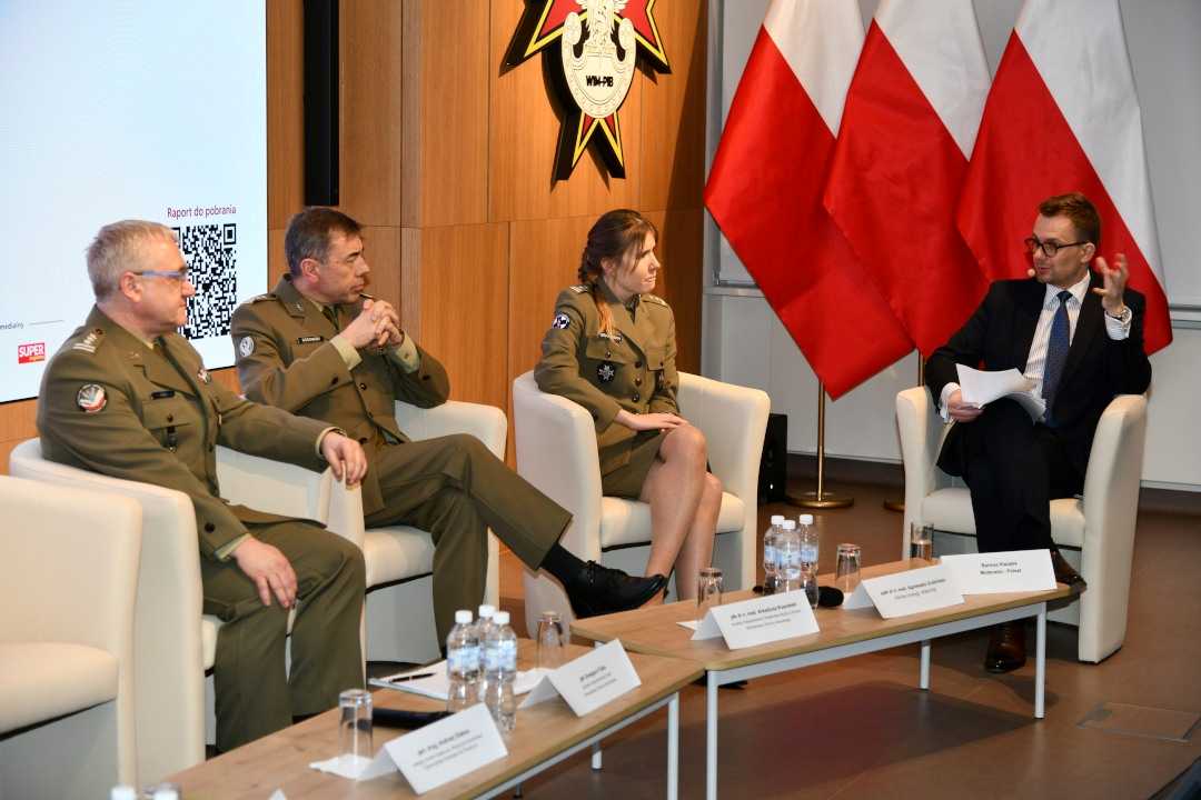 Uczestnicy siedzący w fotelach podczas panelu dyskusyjnego, za ich plecami wyświetlony fragment prezentacji.