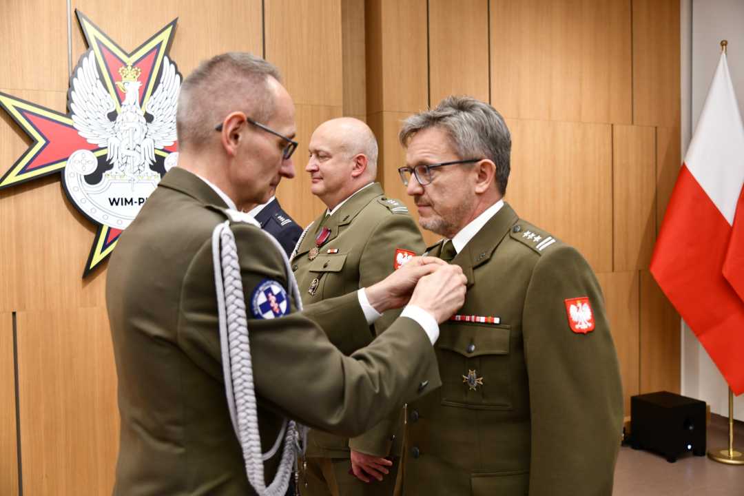 Dyrektor WIM przypina pracownikowi WIM odznaczenie.