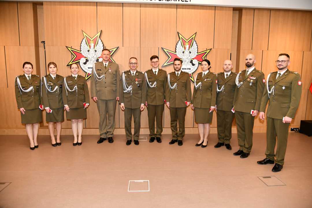 Dyrektor WIM z odznaczonymi pracownikami pozują do zdjęcia grupowego.