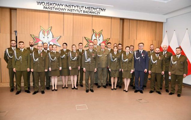 Dyrektor WIM z wszystkimi odznaczonymi pracownikami pozują do zdjęcia.