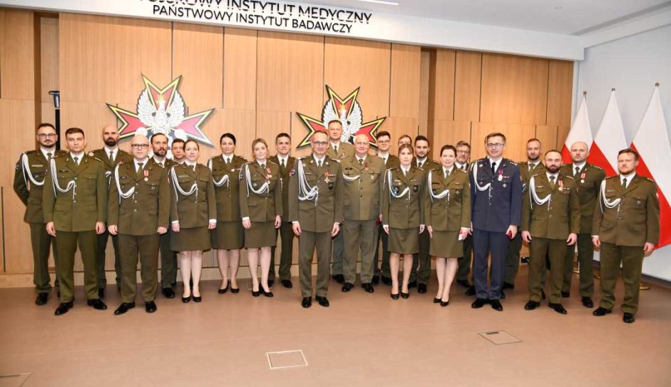 Dyrektor WIM z wszystkimi odznaczonymi pracownikami pozują do zdjęcia.