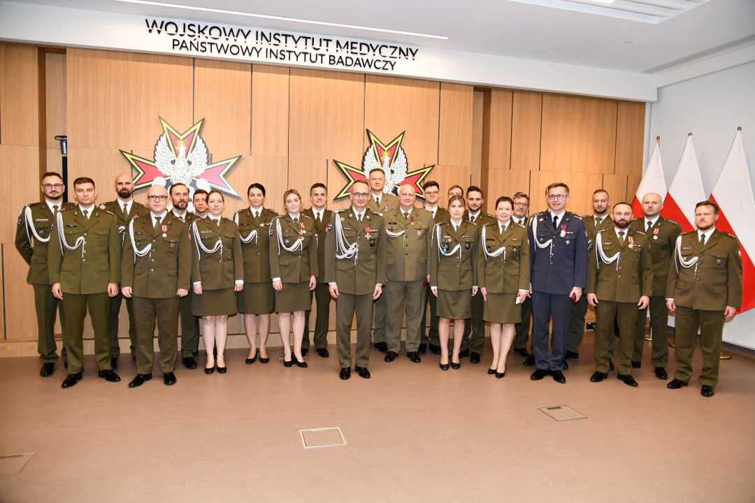 Dyrektor WIM z wszystkimi odznaczonymi pracownikami pozują do zdjęcia.