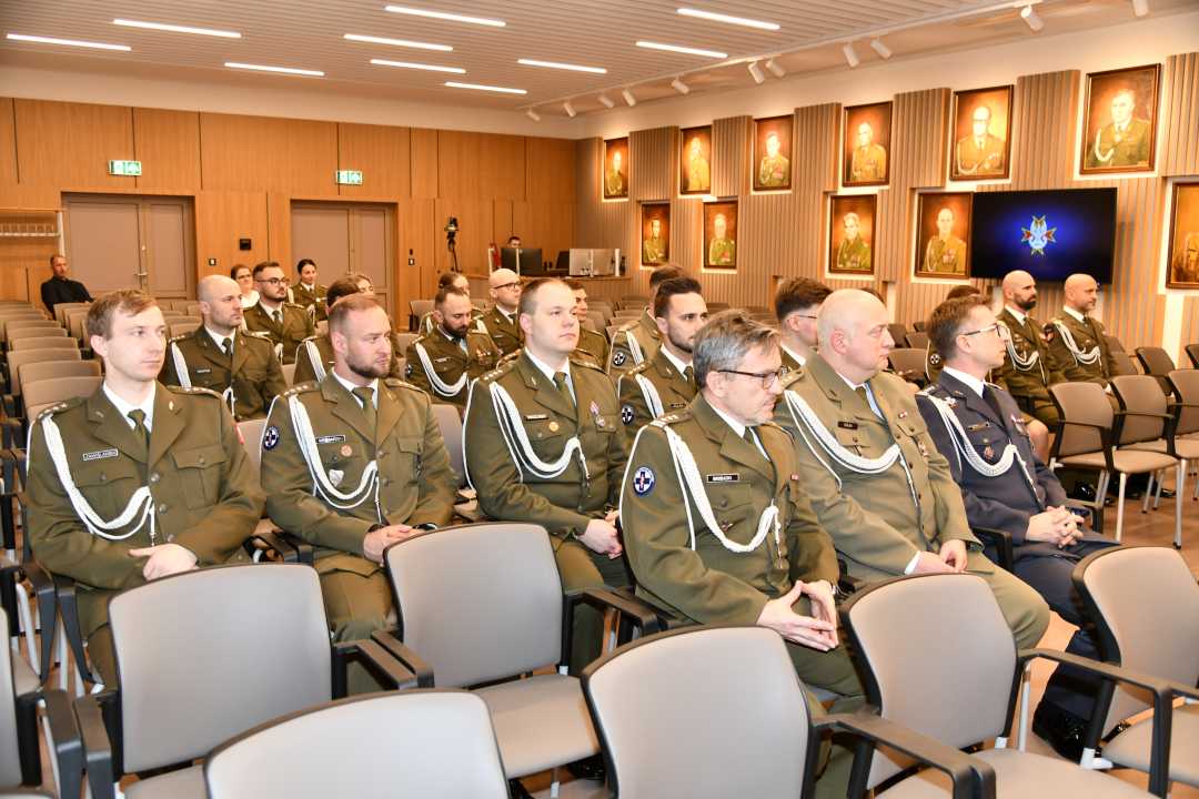 Pracownicy ubrani w wojskowe mundury siedzący na auli WIM podczas uroczystości.