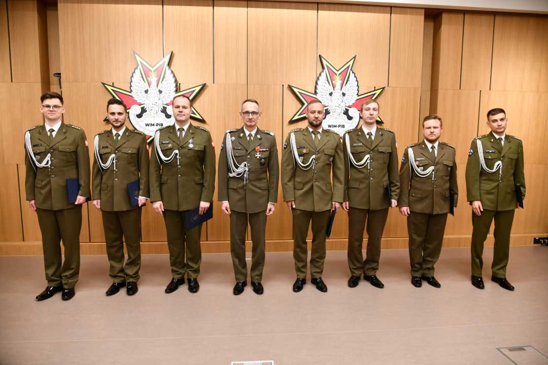 Dyrektor WIM i awansowani pracownicy ubrani w mundury wojskowe pozują do zdjęcia.