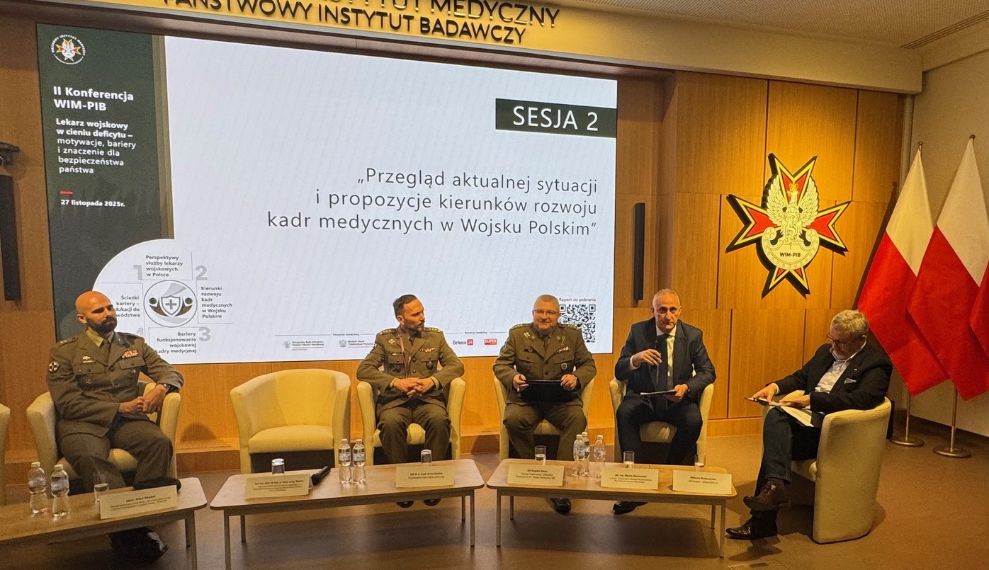 Uczestnicy siedzący w fotelach podczas panelu dyskusyjnego, za ich plecami wyświetlony fragment prezentacji.