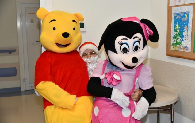 Święty Mikołaj i siedzące na jego kolanach Myszka Miki i Kubuś Puchatek.