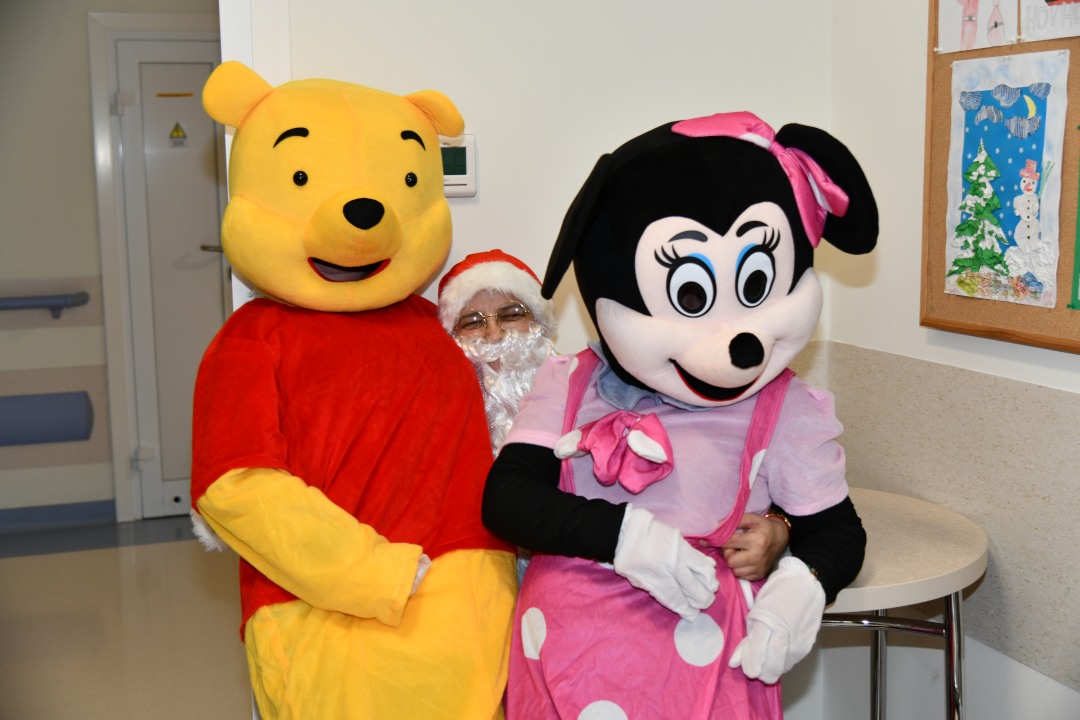 Święty Mikołaj i siedzące na jego kolanach Myszka Miki i Kubuś Puchatek.