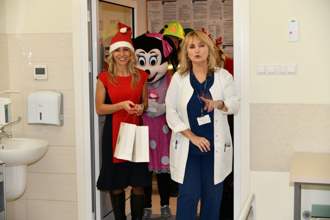 Pomocnicy świętego Mikołaja z prezentami wchodzą do sali szpitalnej.