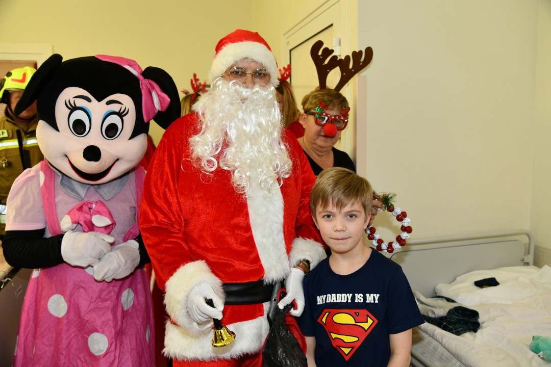 Kilkuletni chłopiec w towarzystwie świętego Mikołaja i jego pomocników.