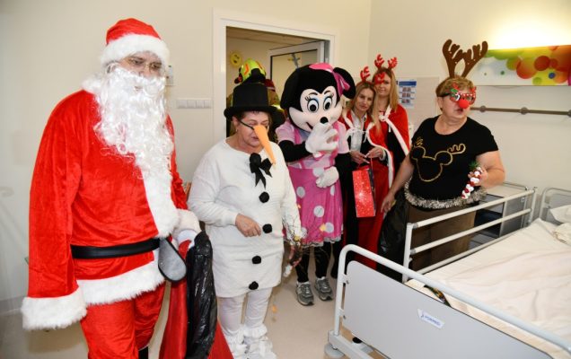 Święty Mikołaj i jego pomocnicy wchodzą do sali szpitalnej.