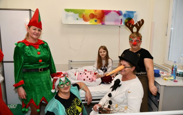 Pomocniczki świętego mikołaja na sali szpitalnej z pacjentami.