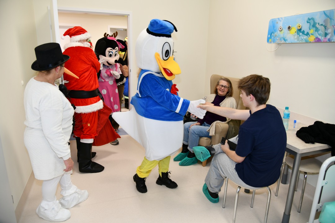 Święty Mikołaj i jego pomocnicy odwiedzają salę nastoletnich pacjentów.