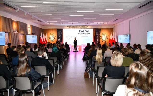 Ujecie auli z siedzącymi słuchaczami konferencji podczas wykładu.