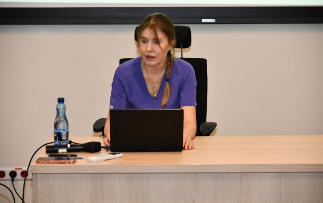Ppłk dr n. med. Agnieszka Grabińska, siedzi przy biurku z laptopem i prowadzi wykład.