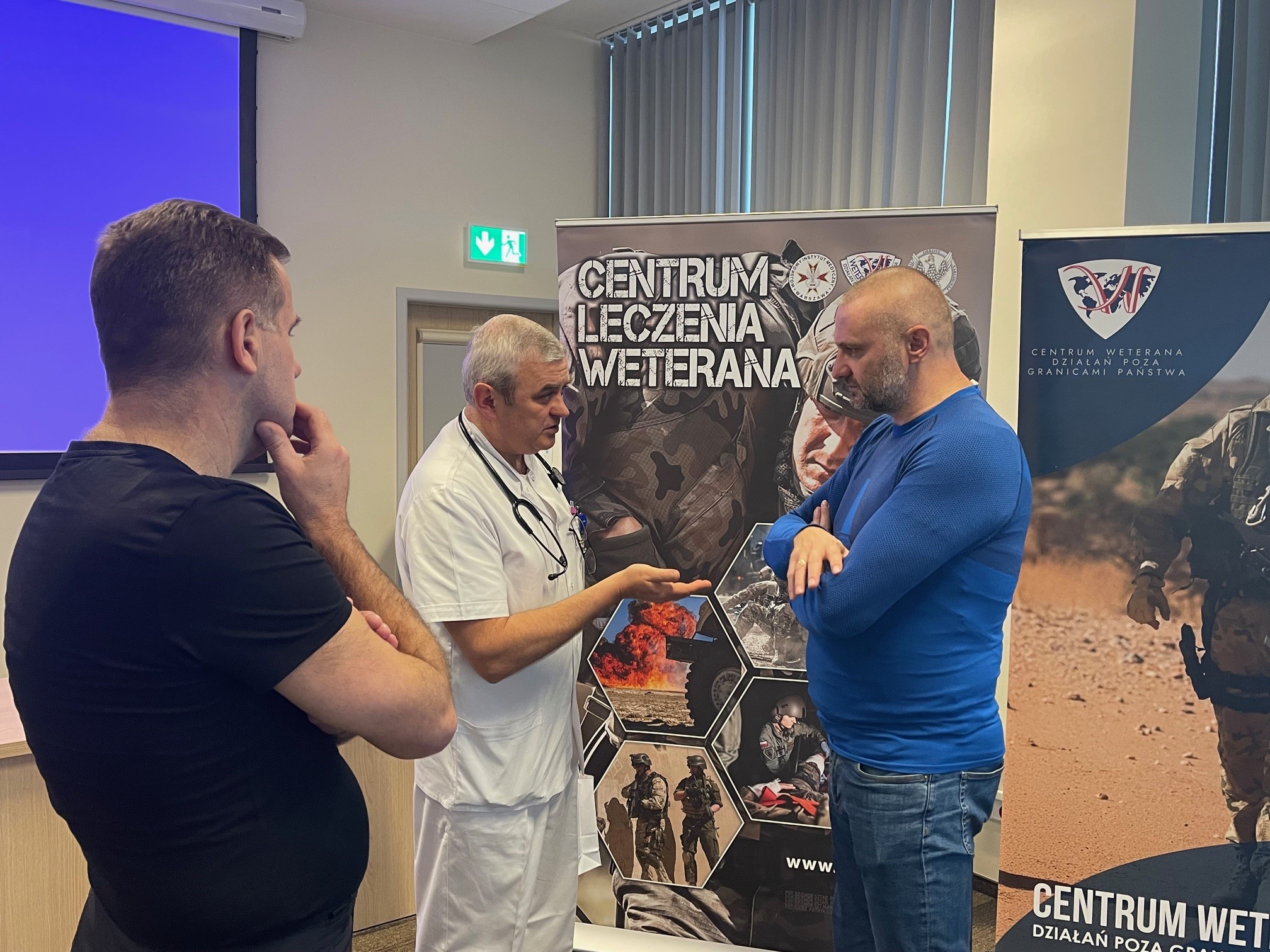 Słuchacze stoją na sali i rozmawiają z pracownikami WIM.