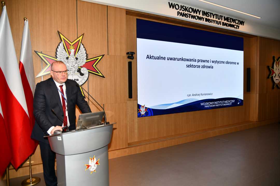 Bartosz Kulczakiewicz podczas przemówienia. Za nim na ekranie slajd tytułowy z konferencji.