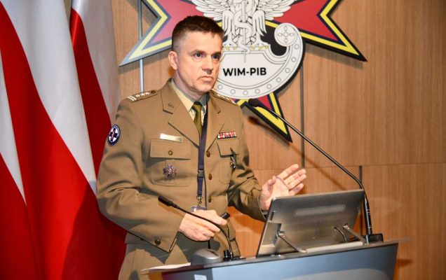 Jarosław Kowal przy mównicy podczas wykładu . Za nim logo WIM.