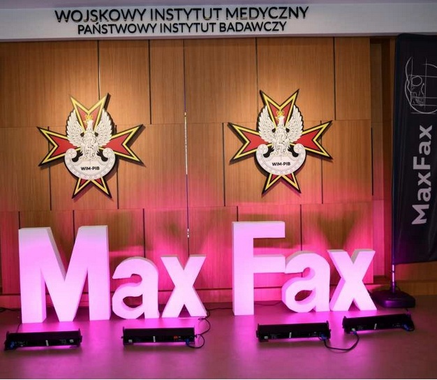 Podświetlony napis Max Fax na auli WIM. Za napisem na ścianę 2 logotypy WIM-PIB.