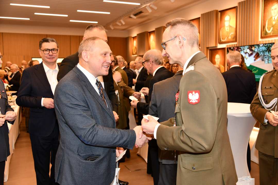 Dyrektor WIM dzieli się opłatkiem z pracownikami i gośćmi.