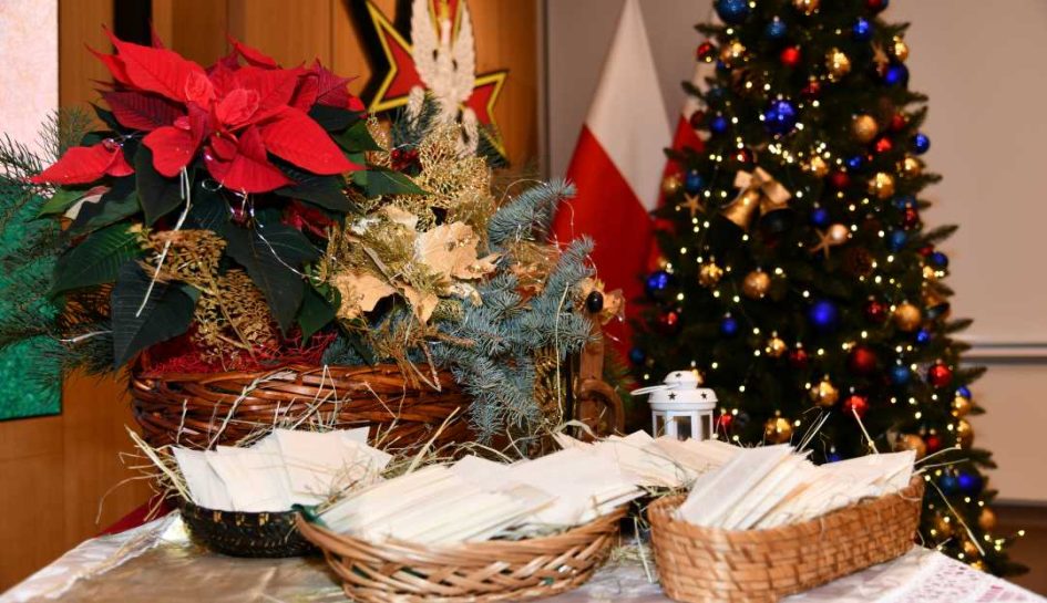 Trzy koszyczki z opłatkiem na stole wysypanym siankiem.