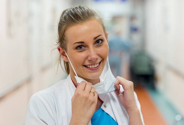 pielęgniarka na korytarzu szpitalnym, uśmiechnięta z zsuniętą z twarzy maseczką