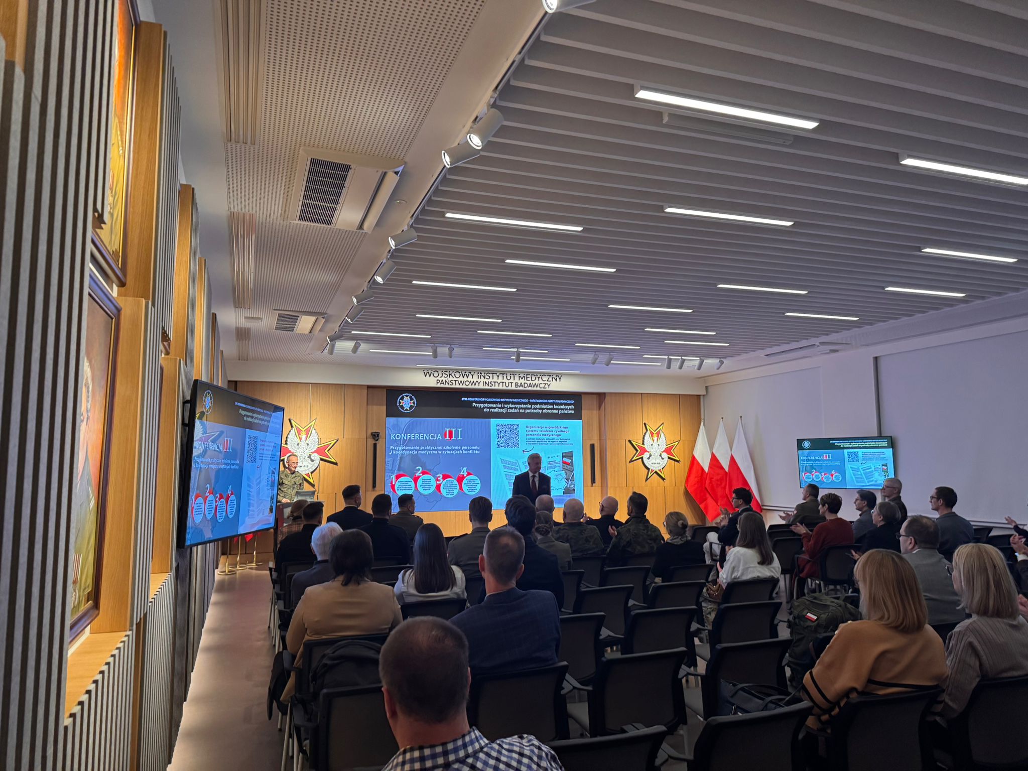 Ujęcie z tyłu sali na słuchaczy konferencji.