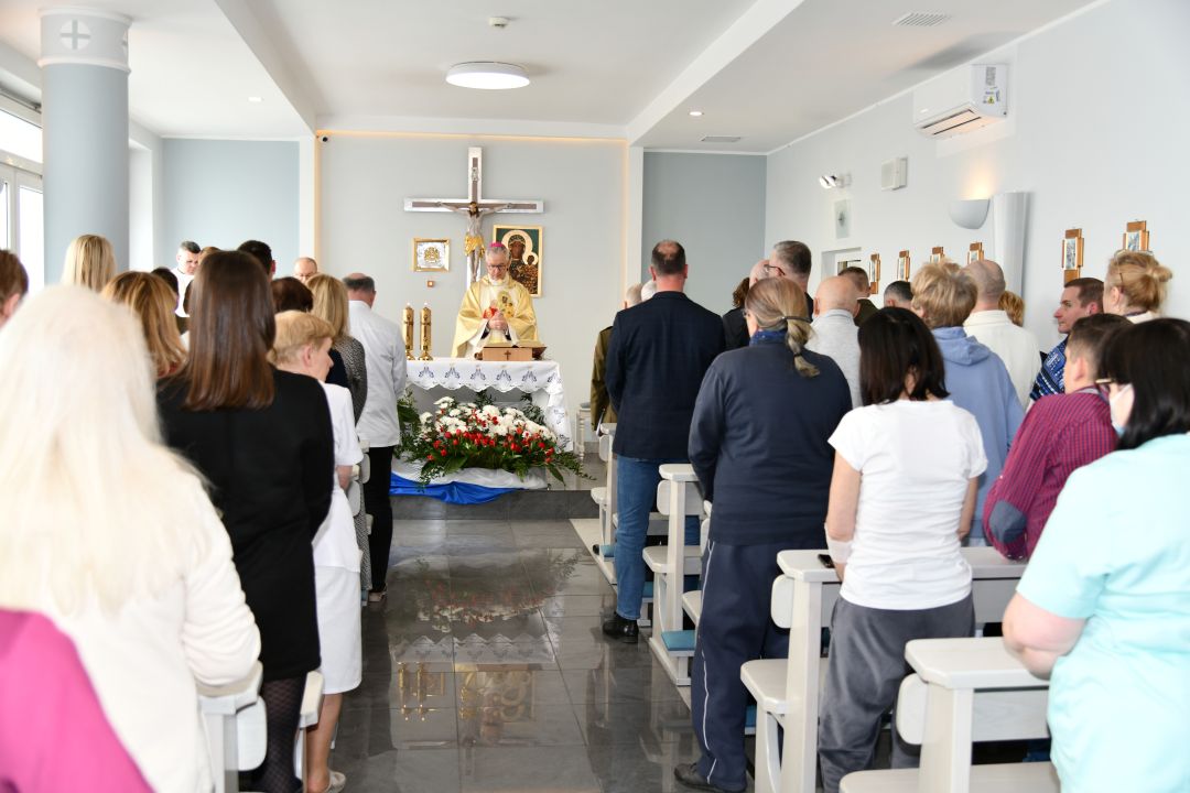 Msza święta. Ujęcie z tyłu kaplicy na ludzi w ławkach i ołtarz.