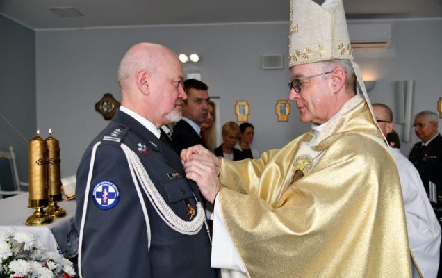 Biskup przypina medal profesorowi Markowi Rękasowi.