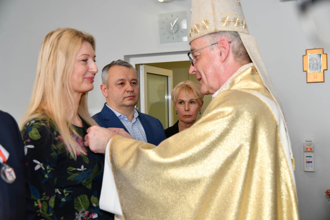 Biskup przypina medal pracownicy WIM.