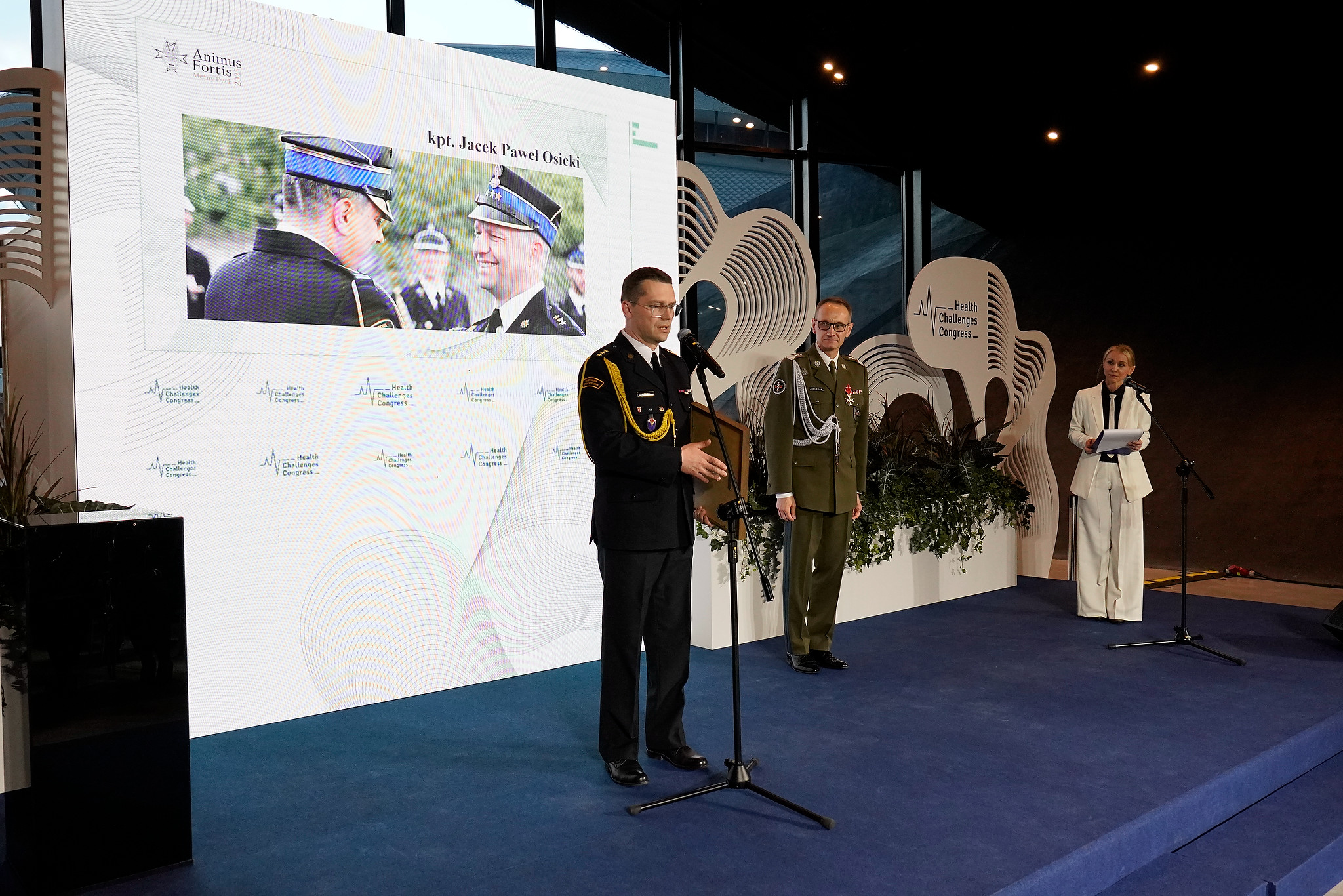Paweł Osicki na scenie przy mikrofonie ze statuetką Animus Fortis.