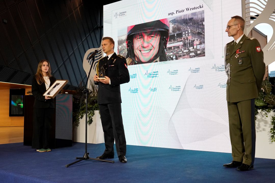 Piotr Wrotecki przy mikrofonie za nimna ekranie plansza z jego zdjęciem.