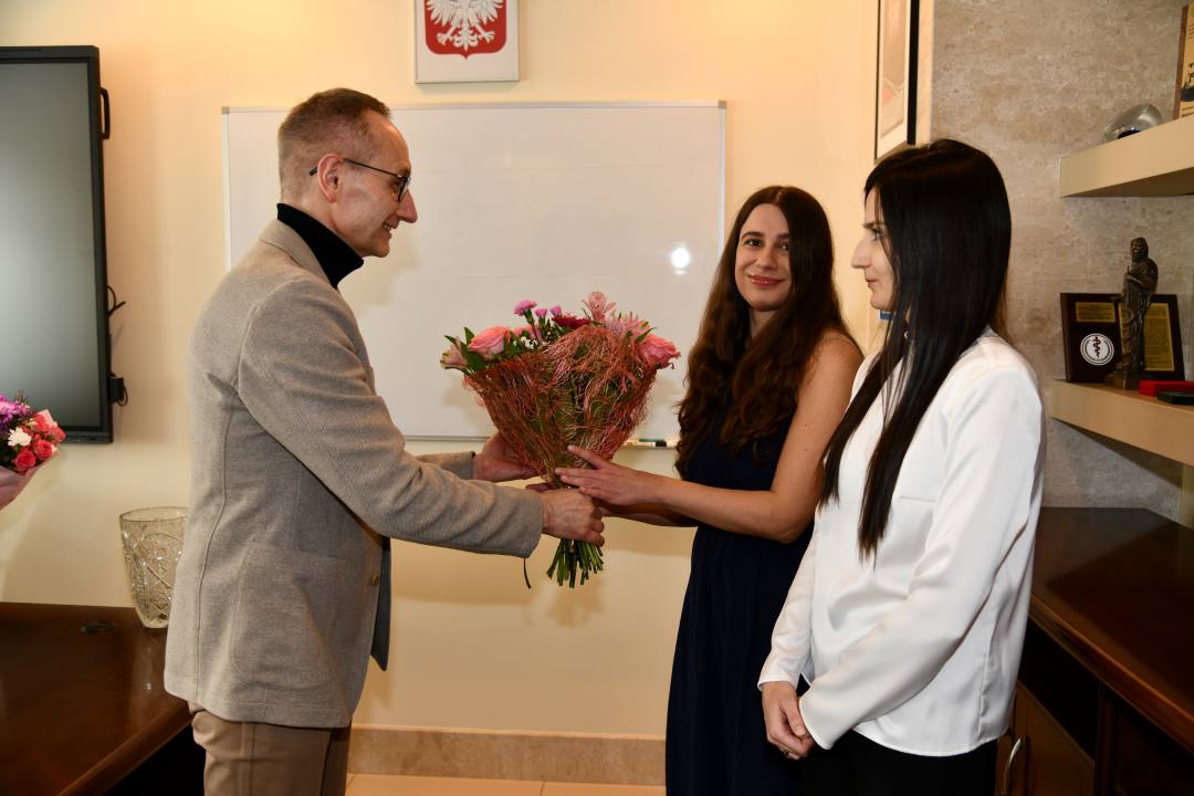 Dyrektor WIM w swoim gabinecie wręcza bukiet kwiatów Dominice Jaskóle-Polkowskiej i Katarzynie Terlikowskiej.
