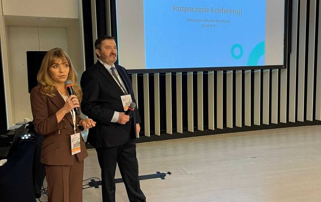 Katarzyna Gniadek-Olejniczak prowadzi prelekcję. Za nią wyświetlacz ze slajdem prezentacji.