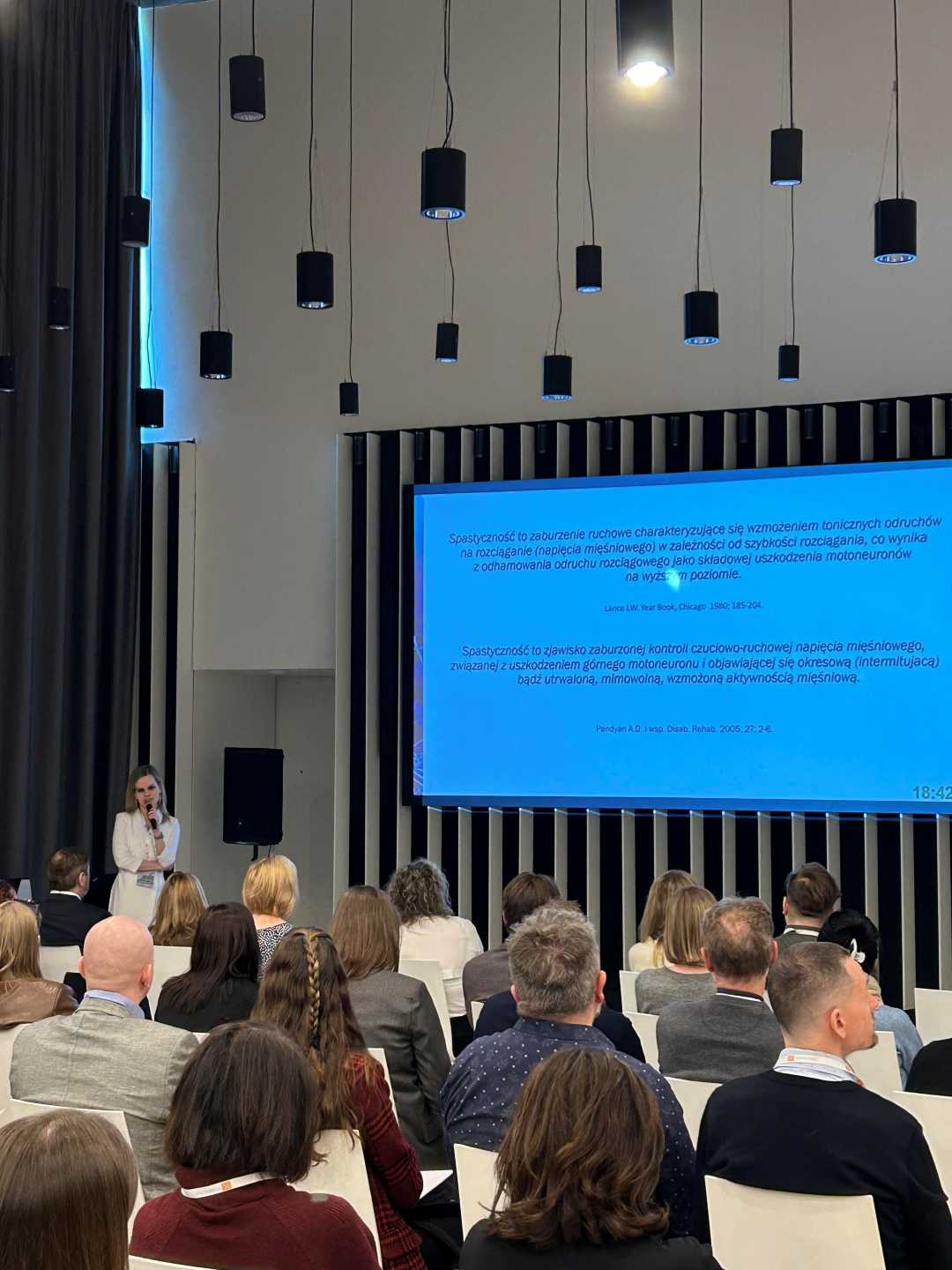 Ujęcie z tyłu sali słuchaczy podczas wykładu na sali konferencyjnej.