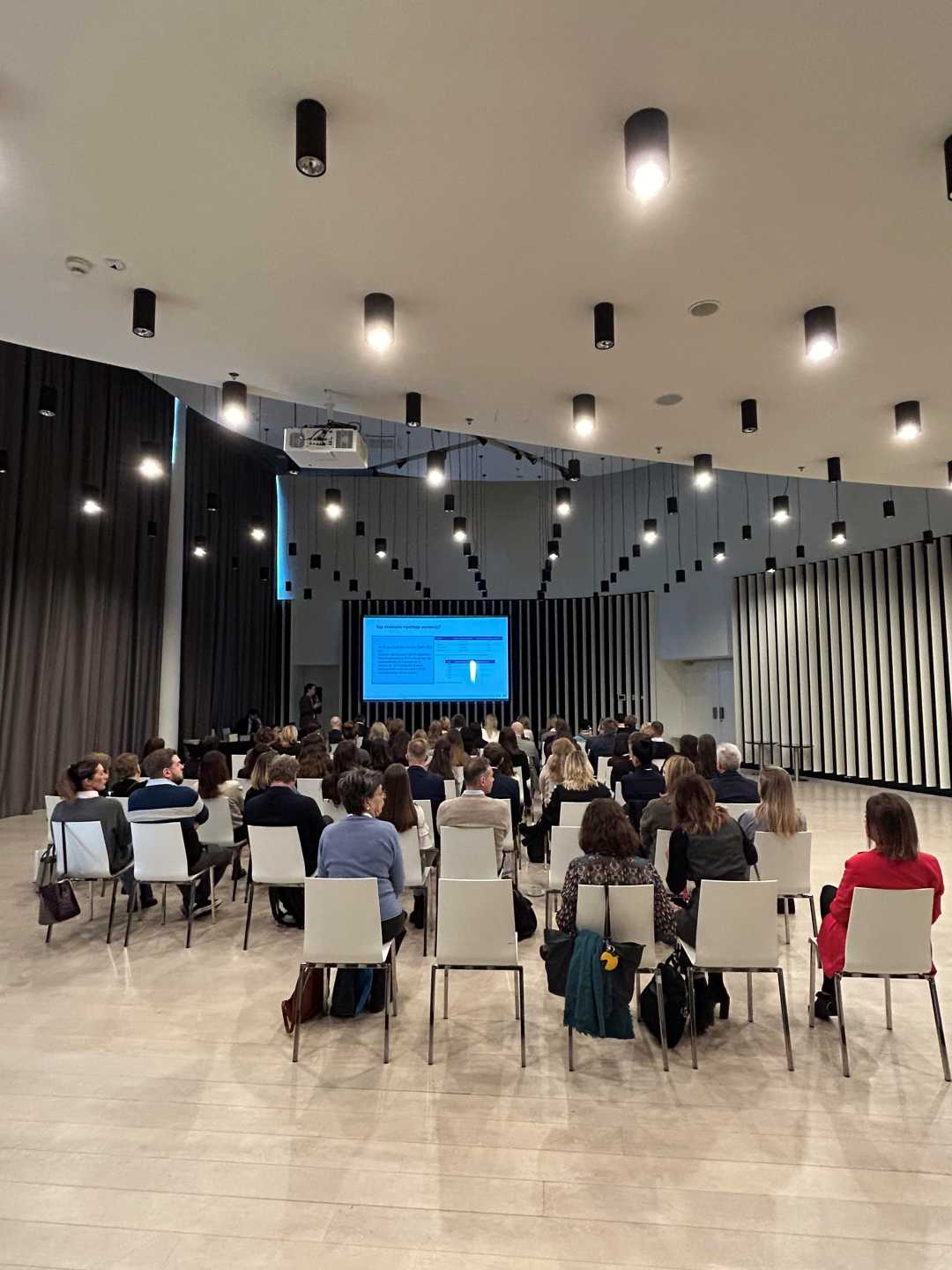 Ujęcie z tyłu sali słuchaczy podczas wykładu na sali konferencyjnej.