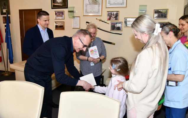 Dyrektor w swoim gabinecie odbiera kartki z życzeniami od dzieci.