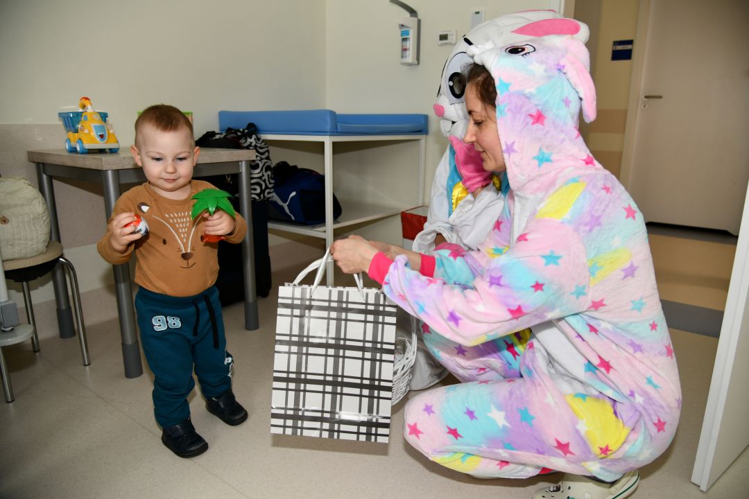 Zajączek wielkanocny w sali szpitalnej kuca przy małym chłopcu.