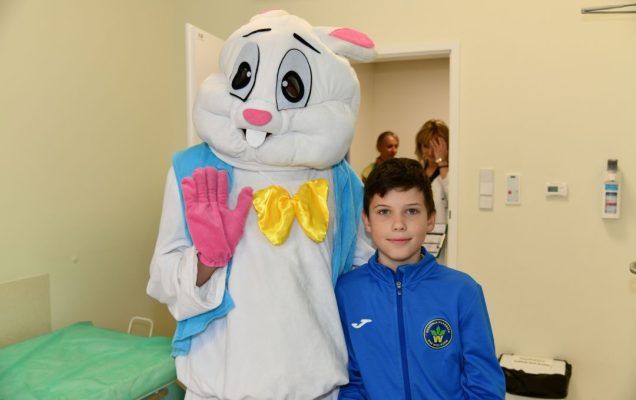 Zajączek wielkanocny w sali szpitalnej z chłopcem pozują do zdjęcia.