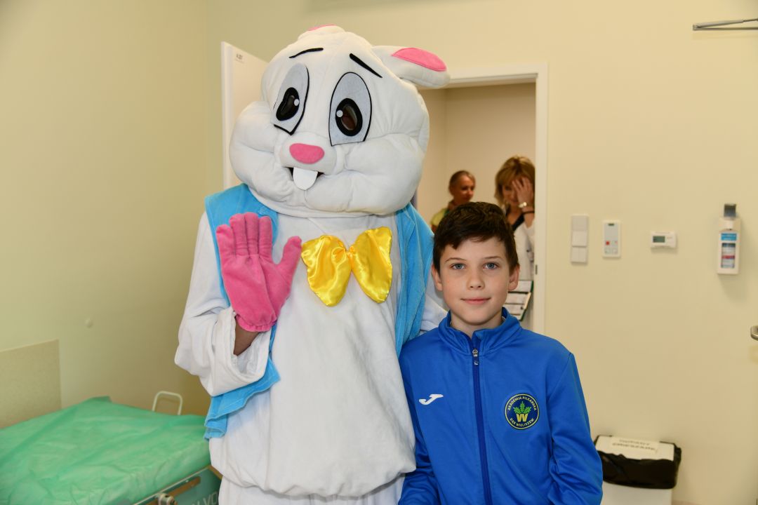 Zajączek wielkanocny w sali szpitalnej z chłopcem pozują do zdjęcia.