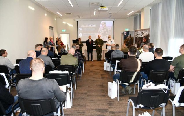 Ujęcie z tyłu sali na uczestników i prowadzących wydarzenie.