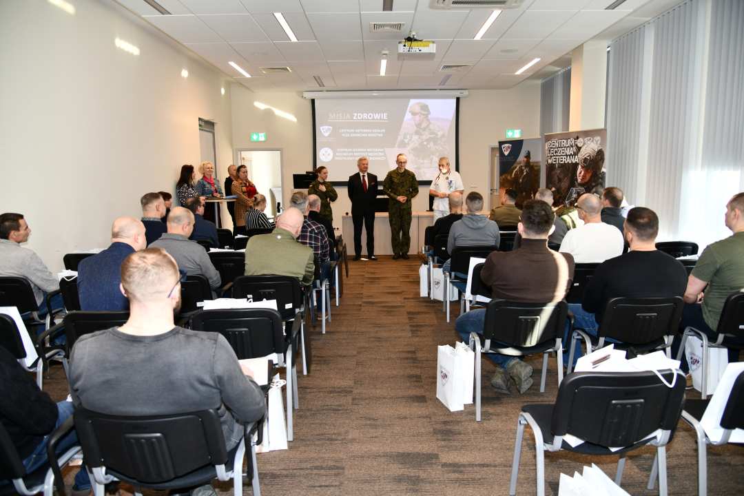 Ujęcie z tyłu sali na uczestników i prowadzących wydarzenie.