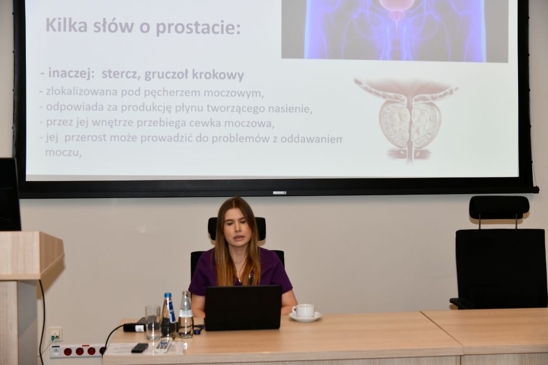 Agnieszka Grabińska za biurkiem podczas wykładu, za nią na ekranie slajd z prezentacji.