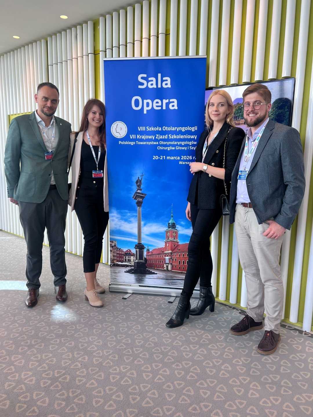 Zdjęcie grupowe prelegentów na tle ścianki z wydarzeniem.