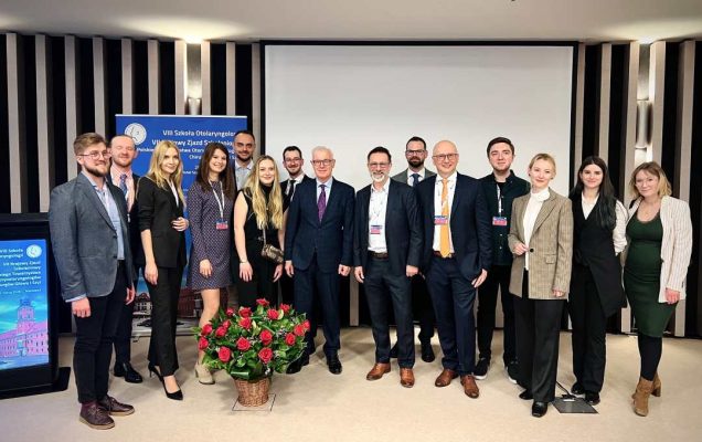 Zdjęcie grupowe prelegentów, przed nimi kosz z bukietem kwiatów.